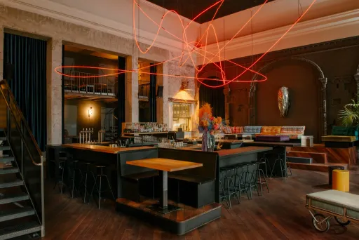Modernes Restaurant mit Holzboden, bunter Einrichtung und leuchtender roter Lichtinstallation.