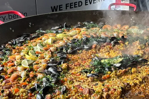 Große Paella-Pfanne mit Muscheln, Limetten, Gemüse und Reis, dampfend gekocht.