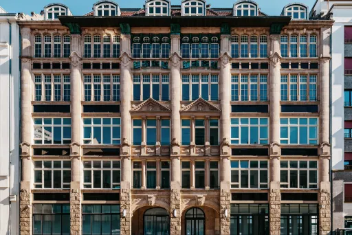 Historische Fassade eines mehrstöckigen Gebäudes mit großen Fenstern und Säulen.