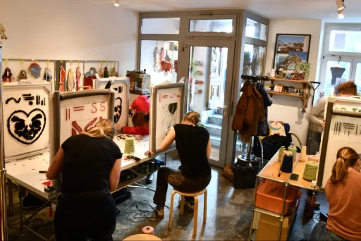 Teilnehmende gestalten bei einem Tufting-Workshop im Künstleratelier von Tufting Berlin eigene Teppichmotive an Tufting-Rahmen.