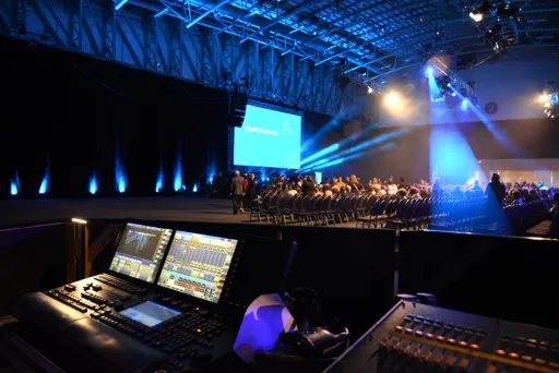 Ton- und Lichttechnikpult bei einer beleuchteten Bühnenshow in großer Halle