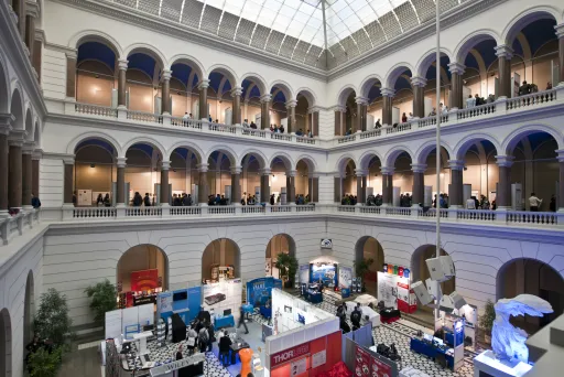Große Messe in einem hellen, historischen Innenhof mit vielen Ständen und Menschen.