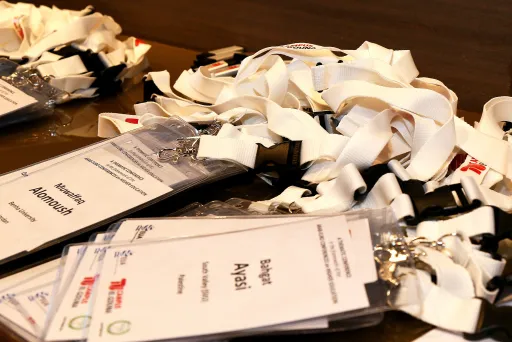 Namensschilder mit weißen Schlüsselbändern liegen auf einem Tisch.