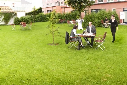 Tagungsgarten mit Grünfläche und kostenfreiem WiFi für Gruppenarbeit und Tagungspausen.