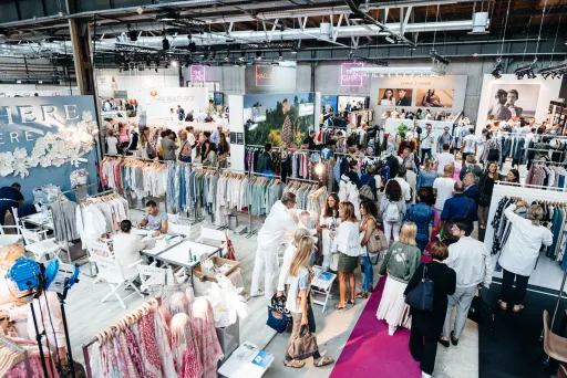Viele Menschen auf einer Modemesse mit Kleiderständen 