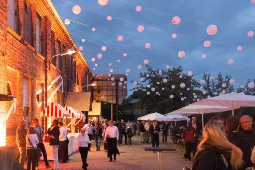 Abendliches Event mit Lichterketten, Menschen und Marktständen.