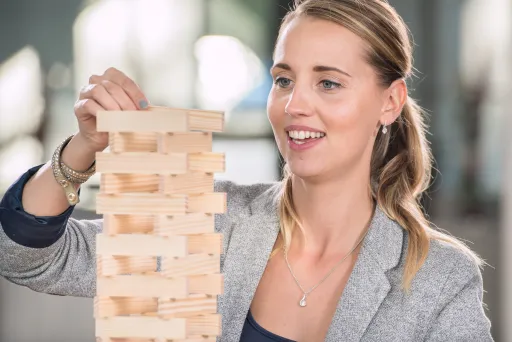 Meeting Guide Berlin Teamgeist Frau baut mit Kapla Steinen einen Turm