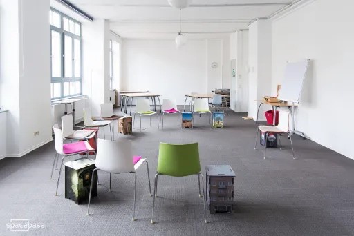 Raum mit grauem Teppich und bunten Stühlen