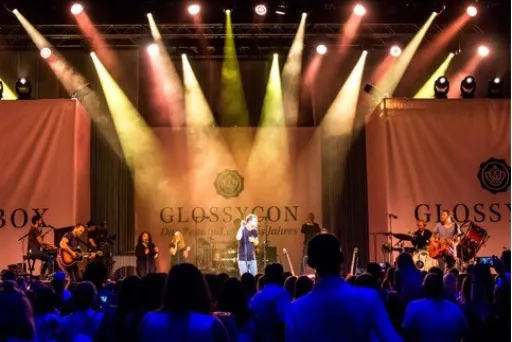 Konzertbühne mit Band, farbige Lichter und jubelndem Publikum.