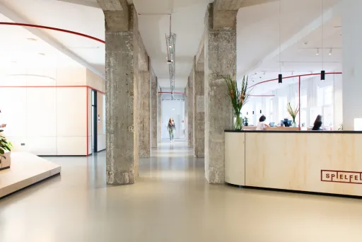 Gehen an zwei Glasschiebetüren vorbei und betreten Sie den Spielfeld-Empfangsbereich, wo unser professionelles Empfangsteam die Gäste begrüßt und sie durch unsere Räumlichkeiten führt. 