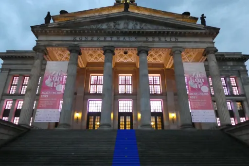 Großes klassisches Gebäude mit Säulen, beleuchtet, blauer Teppich auf der Treppe.