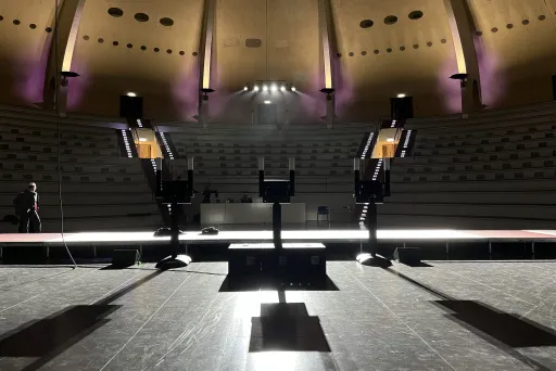 Leerer Vortragssaal mit Podium und lila Beleuchtung, Blick von der Bühne.