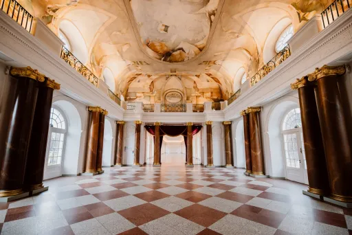 Prunkvoller Saal mit Marmorsäulen, bemalter Decke und großen Fenstern