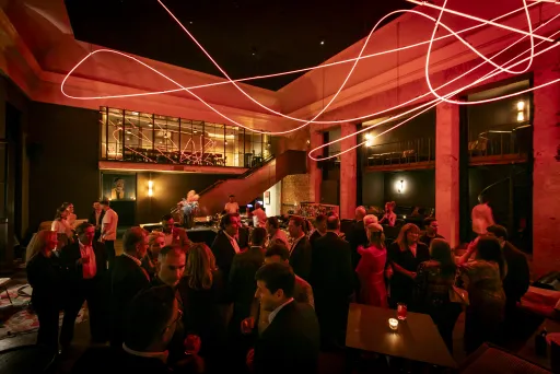 Menschen in eleganter Abendkleidung feiern in stimmungsvoll beleuchtetem Raum.