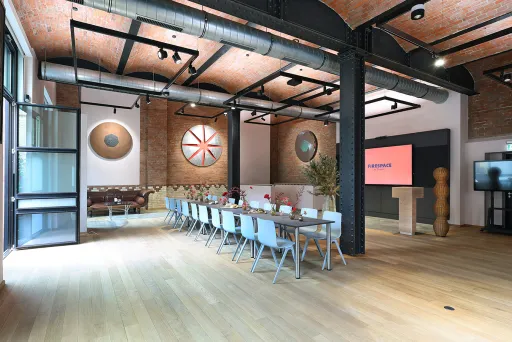 Moderner Konferenzraum mit langem Tisch, Stühlen und Präsentationsbildschirm.