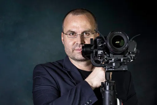 Der Gottwald guckt professionell in die Kamera, mit seiner Kamera, an dieser vorbei.e