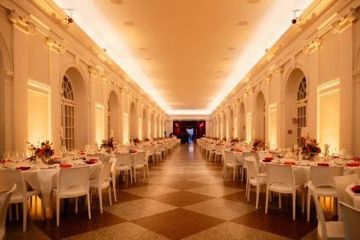 Elegant eingedeckter Festsaal mit weißen Stühlen und warmem Licht.