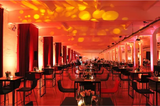 Modernes Restaurant mit stimmungsvoller roter Beleuchtung und festlich gedeckten Tischen.