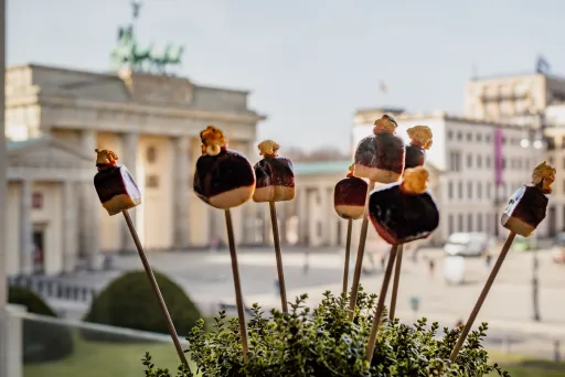 Spieße mit Käse und Trauben, im Hintergrund das Brandenburger Tor in Berlin.