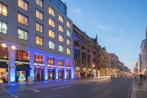 Beleuchtete Straße mit modernen und historischen Gebäuden bei Sonnenuntergang