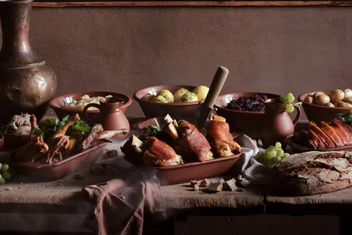 Rustikaler Tisch mit Braten, Kartoffeln, Rotkohl und frischem Brot.