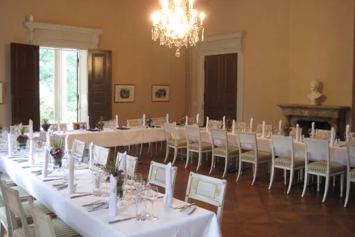 Eleganter Speisesaal mit weiß gedeckten Tafeln und Kronleuchter.