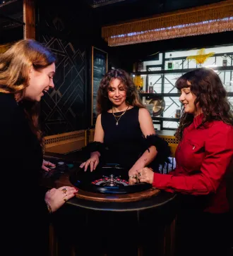 Three women happily playing roulette at a casino table.