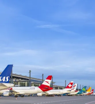 Mehrere Flugzeuge verschiedener Airlines stehen nebeneinander am Gate eines Flughafens.