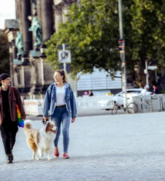 Two people with a dog are out and about in Berlin.