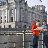 Touristen mit Stadtplan vor dem Spreeufer mit Blick auf den Berliner Reichstag