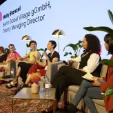 Paneldiskussion beim BESTIVAL 2025 in Berlin: Sechs Frauen sitzen auf einer Bühne in einer modern eingerichteten Gesprächsrunde. Eine der Sprecherinnen spricht ins Mikrofon, im Hintergrund ist der Name „Molly Stenzel“ auf einer Leinwand zu sehen.