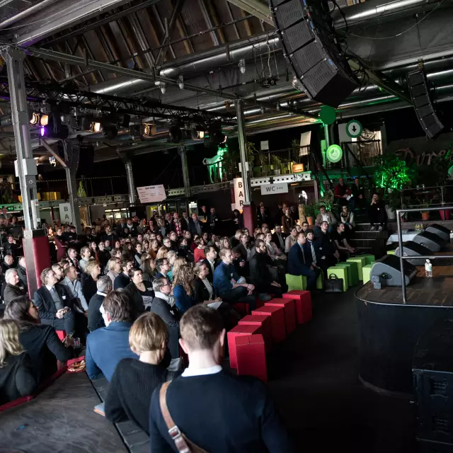 Menschen sitzen vor der Bühne beim 2. Berlin MICE Summit im Festsaal Kreuzberg, Eröffnung der Veranstaltung durch den Staatssekretär Christian Rickerts