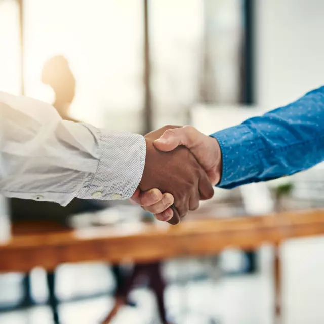 Two business partners shake hands in a business setting