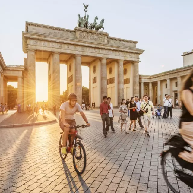 Menschen vor dem Brandenburger Tor auf Fahrrädern im Sonnenuntergang