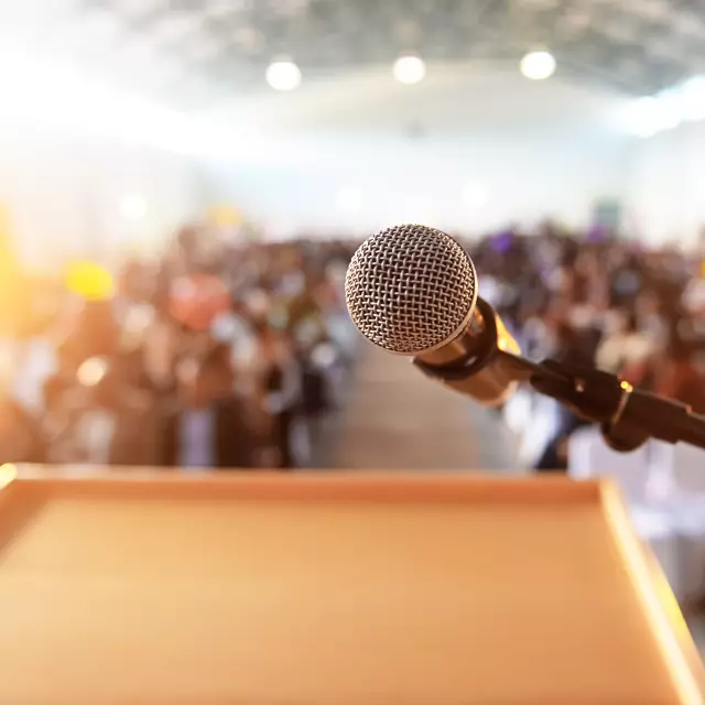 Microphone in front of the podium with crowd in the background in bright sunshine