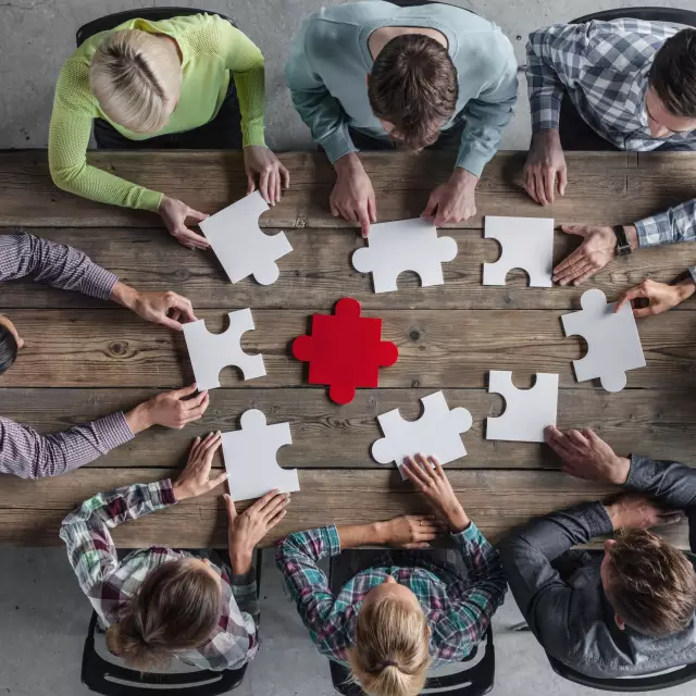 A team assembles puzzle pieces at a meeting