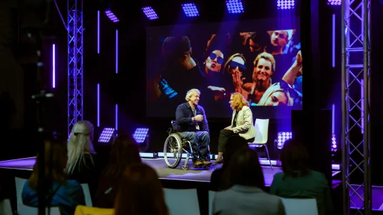 Two people are on stage during an evening programme.