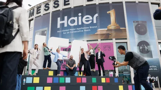 People posing on a colorful stage outside Messe Berlin exhibition center.