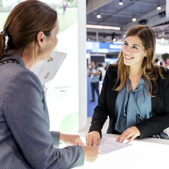 Ein Gespräch zwischen zwei Frauen auf einer Messe, die sich anlächeln
