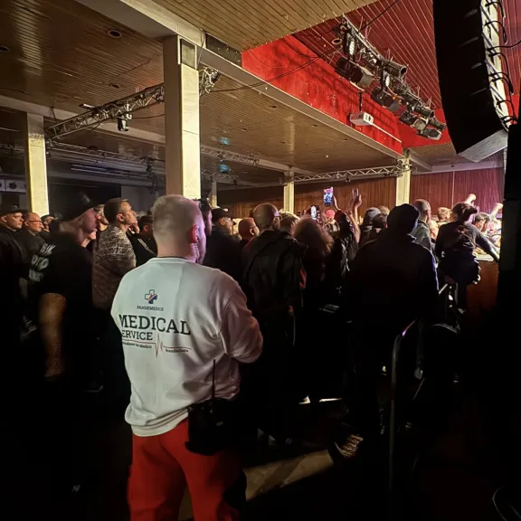 Menschenmenge bei Konzert, Sanitäter in weißer Jacke im Vordergrund