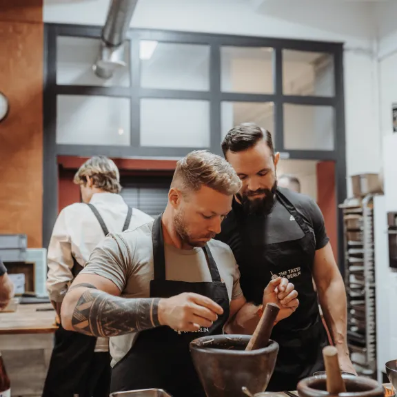 Zwei Männer arbeiten gemeinsam mit Mörsern in einer modernen Küche.