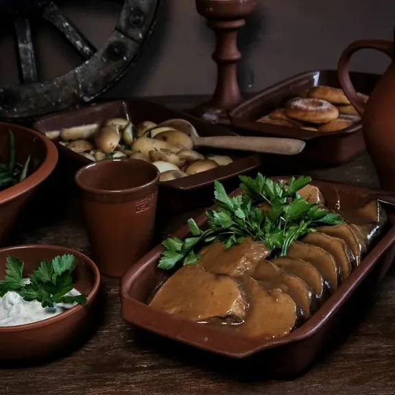 Rustikales Essen in braunen Keramiktellern, Bohnen, Brot, Bratensoße und Kräuter.