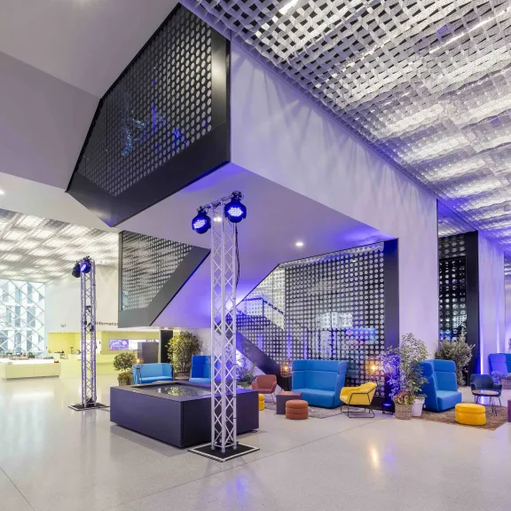 Modernes, farbenfrohes Hotellobby mit Sitzbereichen und großer Glasfront.