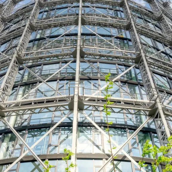 Großes rundes Industriegebäude mit Stahlstreben und Glasfassade, Blick von unten.