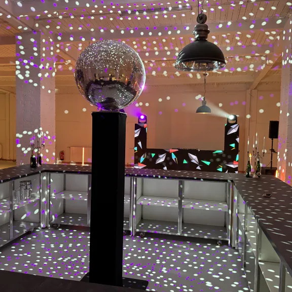 Bar mit Discokugel und bunten Lichtpunkten in modernem Partyraum