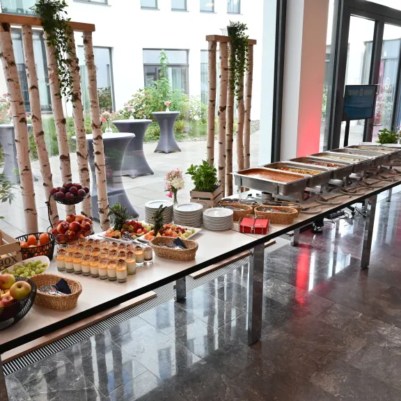 Buffet-Tisch mit Obst, Gemüse, Eiern und weiteren Speisen in modernem, hellem Raum.