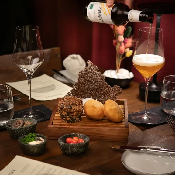 Ein Glas wird mit Bier gefüllt, daneben Vorspeisen auf einem Holztisch im Restaurant.
