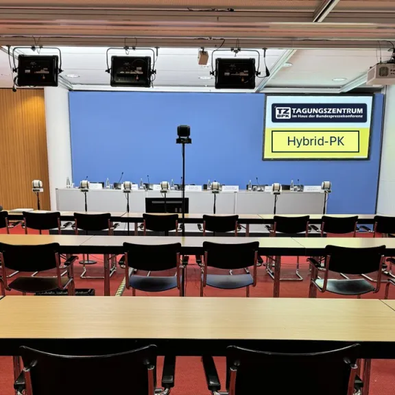Leerer Konferenzraum mit Stühlen, Tischen und einem Podium vorne.