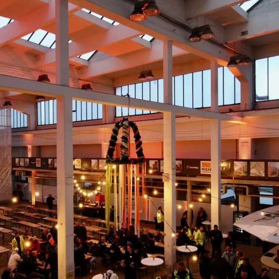 Große, helle Halle mit vielen Menschen, Lichterketten und festlicher Dekoration.