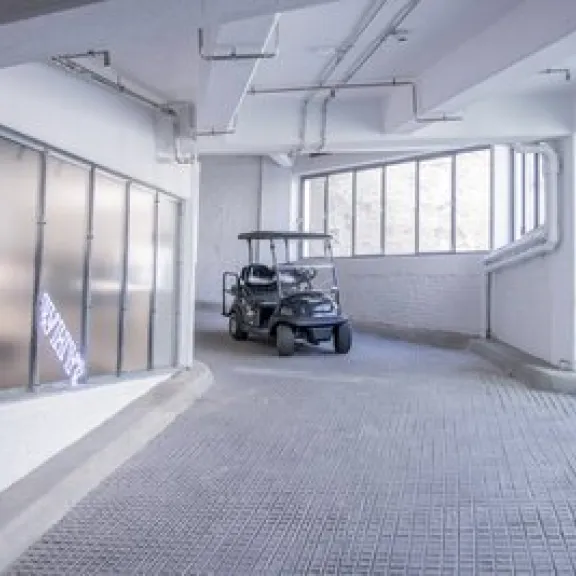 Golfcart steht in heller Tiefgarage mit großen Fenstern.